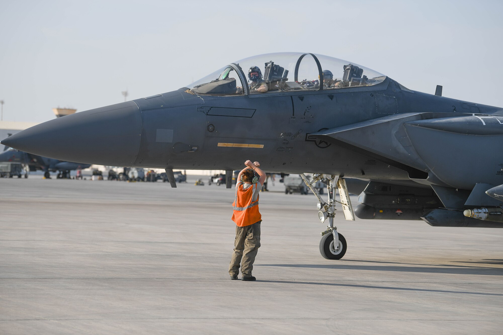 A crew chief from the 380th Expeditionary Aircraft Maintenance Squadron marshals a U.S. Air Force F-15E Strike Eagle to park Oct. 18, 2019, at Al Dhafra Air Base,