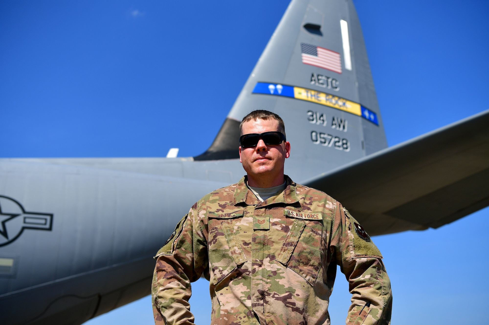 A man in the OCP uniform stands in front of a C-130J.