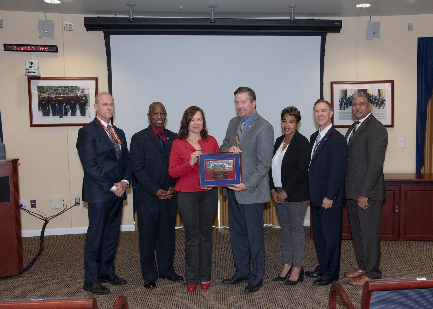 Five men and two women pose with a plaque after the HQC Hispanic Heritage Month observance.