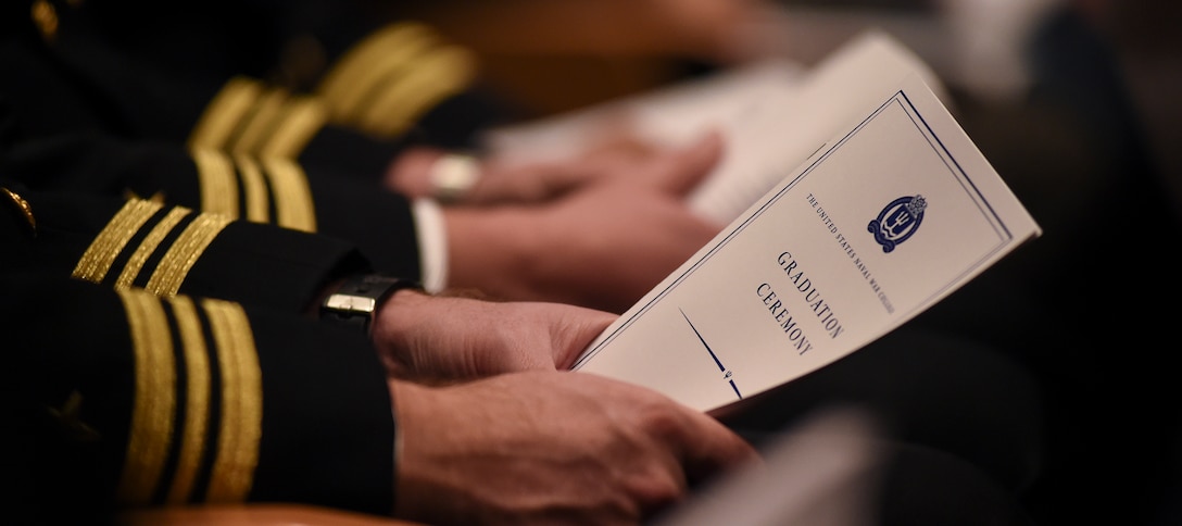 A U.S. Naval War College student holds a program during his graduation ceremony held at NWC’s Spruance Auditorium. Fifty-two students from the College of Naval Warfare and College of Naval Command and Staff were recognized for their achievements and received either a Master of Arts degree in National Security and Strategic Studies or Master of Arts degree in Defense and Strategic Studies during the ceremony.