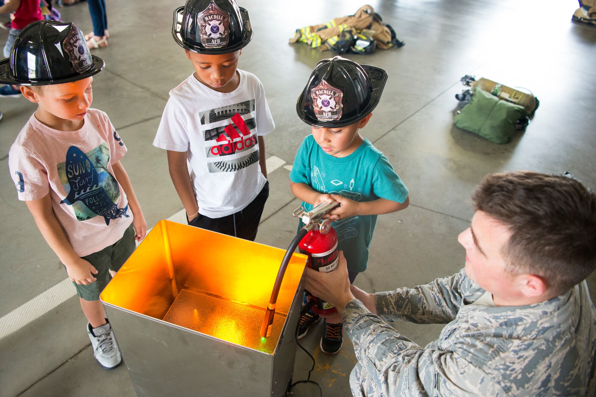 A 6th Civil Engineer Squadron Fire Emergency Services Flight firefighter teaches Tinker K-8 Students how to operate a fire extinguisher during Fire Prevention Week at MacDill Air Force Base, Fla., Oct. 8, 2019.
