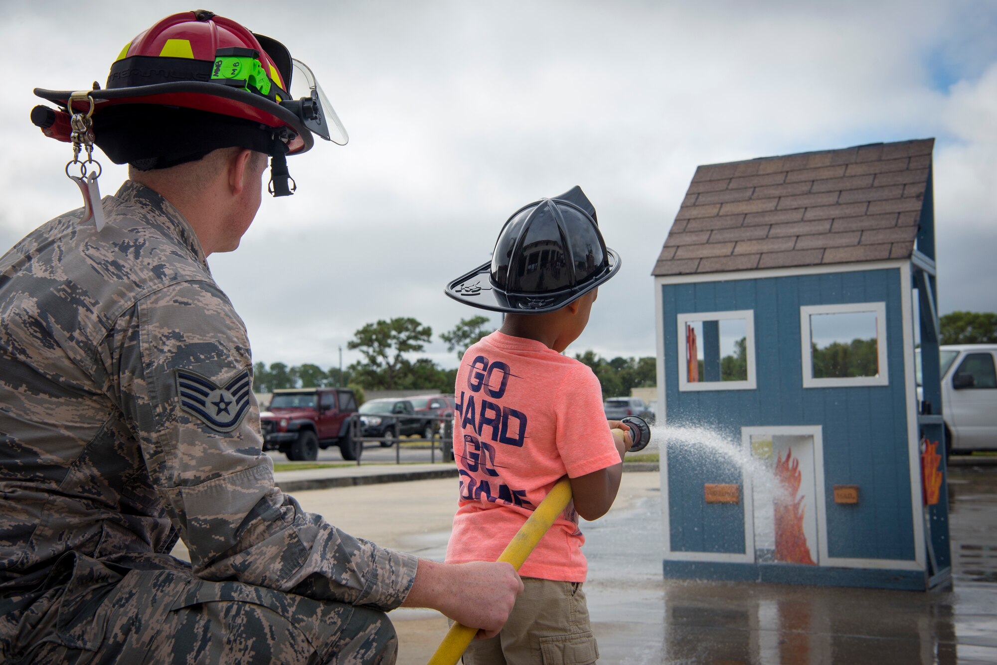 A 6th Civil Engineer Squadron Fire Emergency Services Flight firefighter teaches a Tinker Elementary student how to operate a fire hose during Fire Prevention Week at MacDill Air Force Base, Fla., Oct. 8, 2019.