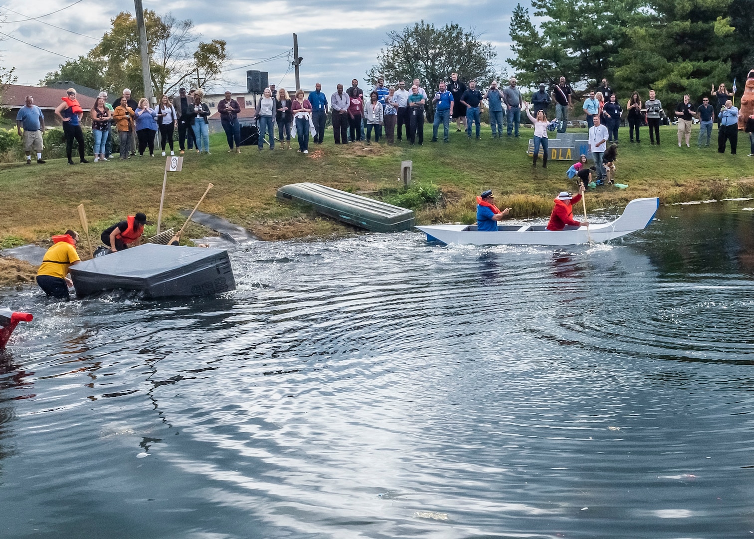 Two men pull boat out of the water after capsizing.