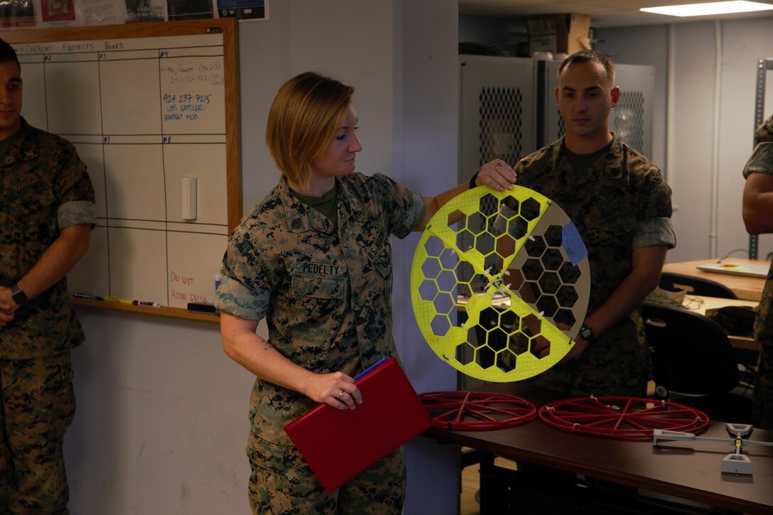 U.S. Marine Staff Sgt. Elissa Pedelty receives $1,000 and a Navy and Marine Corps Achievement Medal for her winning idea in designing an Environmental Control Unit (ECU) duct cover at MakerSpace, Camp Lejeune, North Carolina, on Oct. 16, 2019. MakerSpace facilitates the 2nd Marine Logistics Group Commanding General’s Innovation Challenge, where Marines and Sailors submit innovative ideas to design an interesting culture that explores new ideas to improve policies, procedures or products.  (U.S. Marine Corps photo by Sgt. Ashley Lawson)