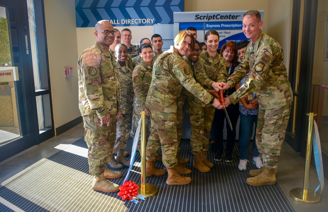 Col. David S. Miller, 377th Air Base Wing installation commander, Master Sgt. Raechael Evans, 377th Medical Group pharmacy flight chief, and staff of the 377th MDG cut the ribbon during the grand opening ceremony of the new ScriptCenter kiosk at the Base Exchange Oct. 16. Roughly 800 patients visit the BX Pharmacy on high volume days. The ScriptCenter can re-direct 350 of those patients, increasing access to care and time away from the duty section for active duty service members. (U.S. Air Force photo by Jessie Perkins)