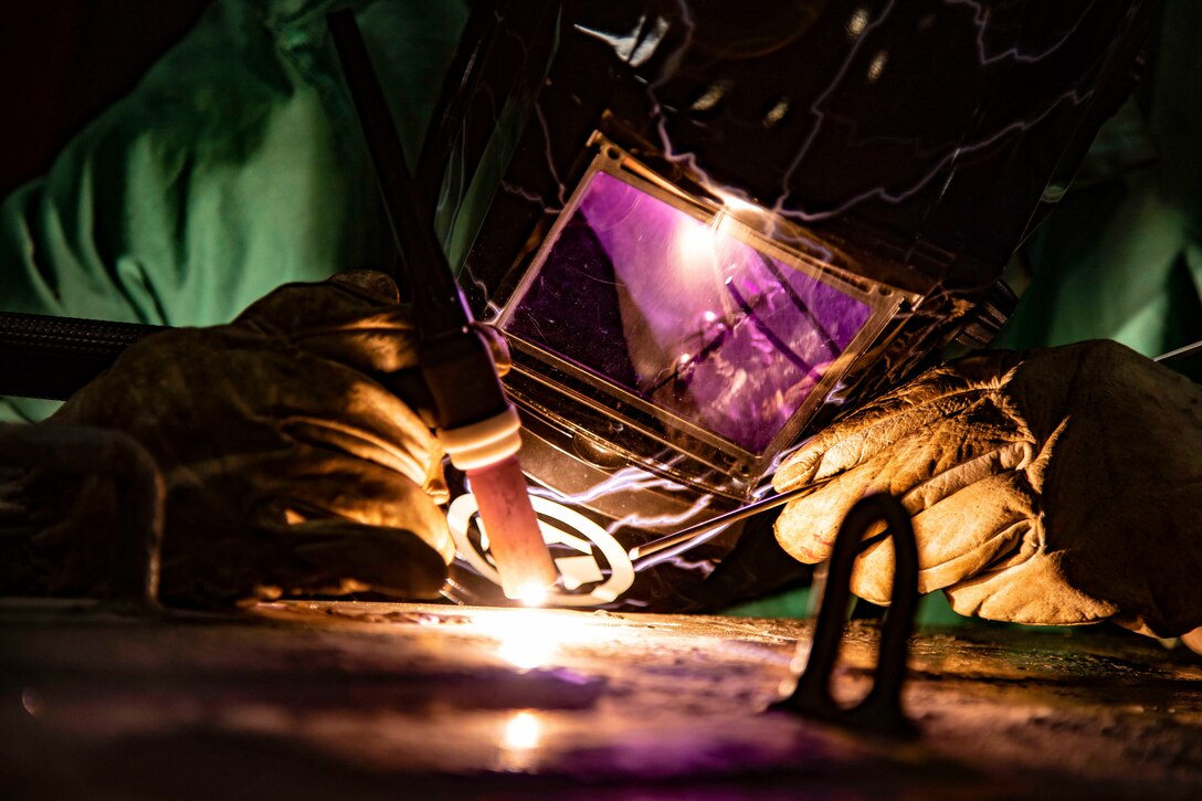 A sailor welds onto a surface.