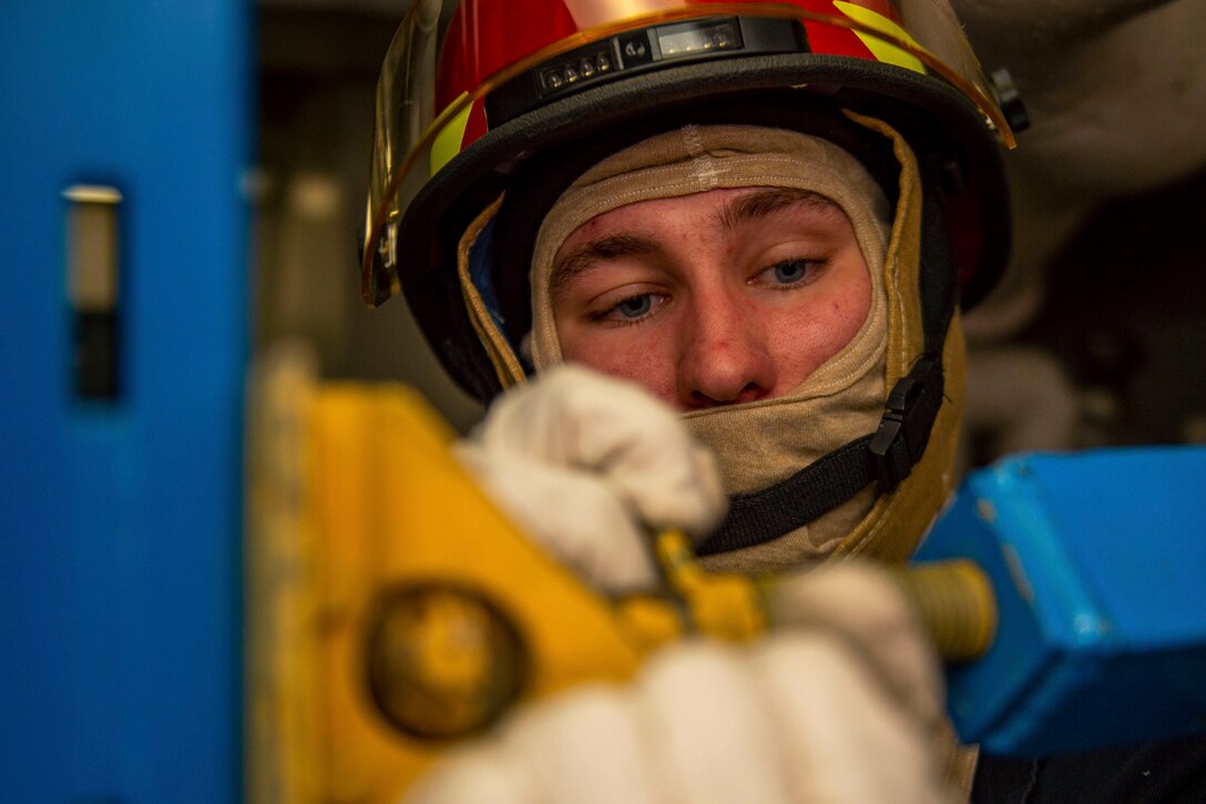 A sailor uses a tool to tighten shoring .