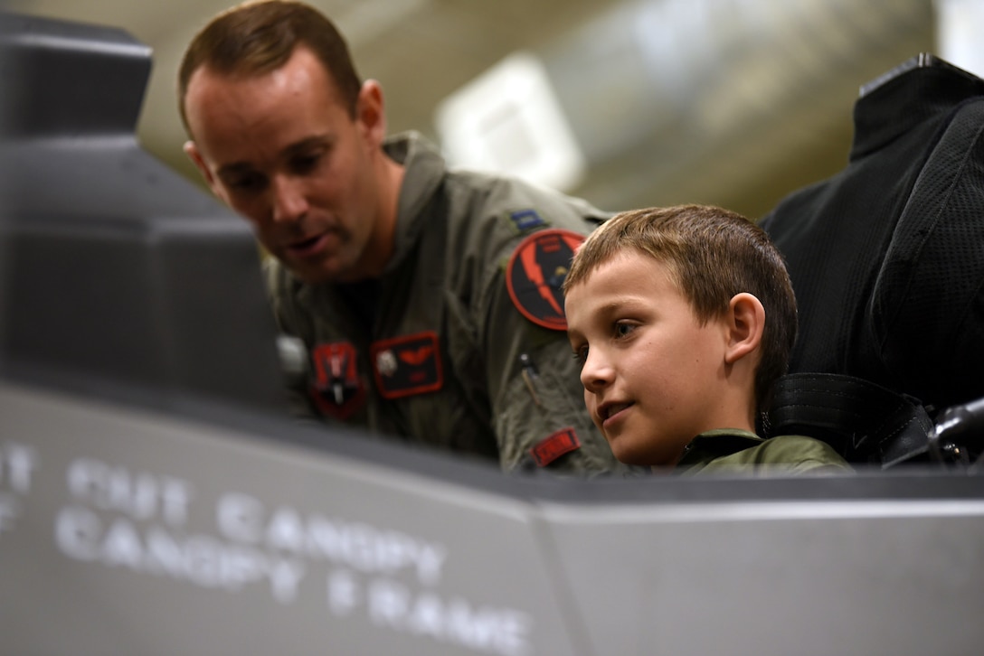Brody, with Make-A-Wish Utah, listens as Capt. Buck Horn, an F-35A Lightning II pilot shows him around the cockpit of an F-35A egress trainer. A group of children visited the 388th Fighter Wing at Hill Air Force Base, Utah, where they spent the day learning what it's like to be a pilot. They received flight suits, name tapes, patches, and wings. (U.S. Air Force photo by Micah Garbarino)