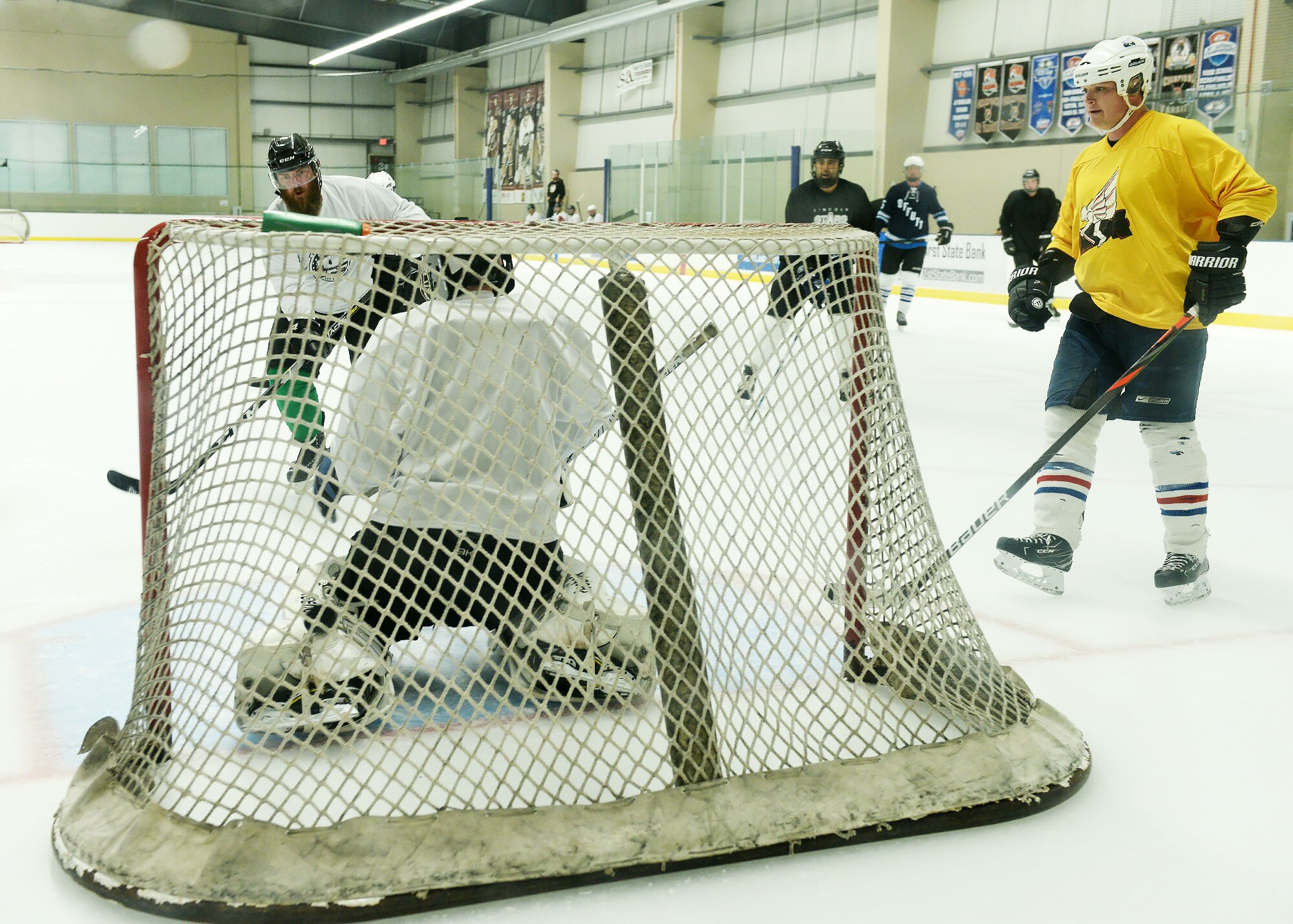 The Nebraska Warriors hockey team scrimmages at Ralston Arena in Ralston, Nebraska. Several players approach the net as a goalie tries to defend.