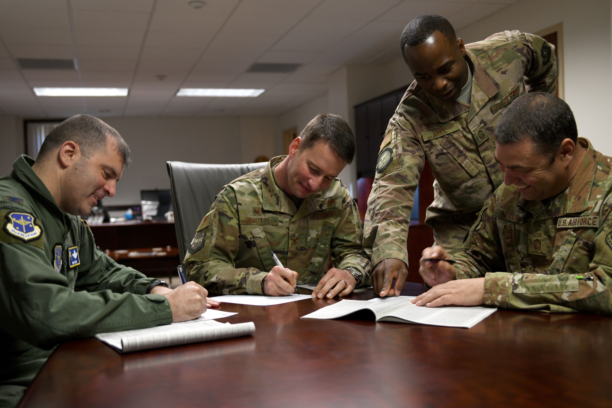 Men in military uniforms sign a piece of paper.