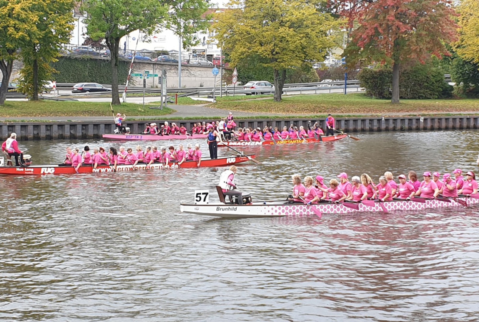 three dragon boat teams paddle in the water