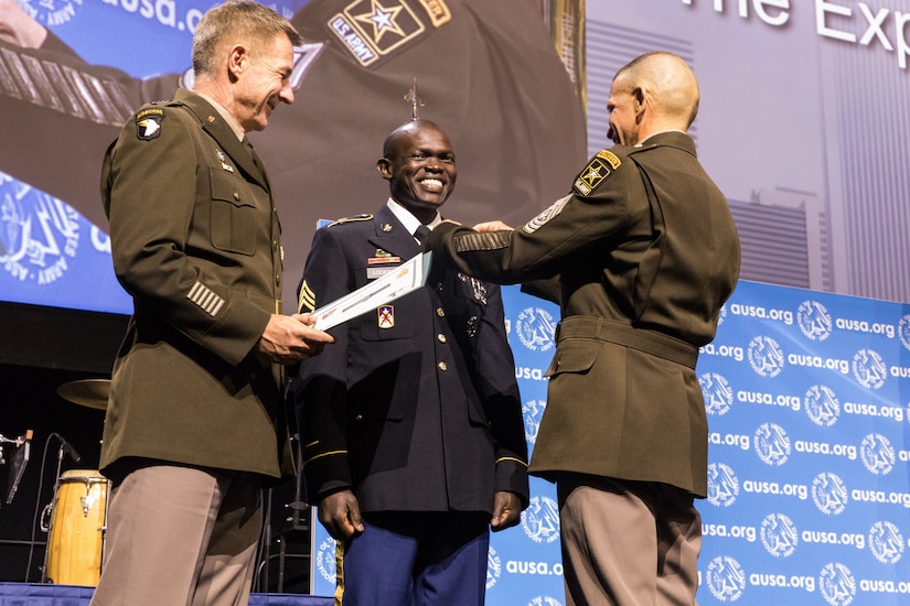 Sgt. 1st Class Anthony Lodiong receives his Expert Soldier Badge from Army Chief of Staff Gen. James C. McConville and Sgt. Maj. of the Army Michael A. Grinston at the at the Eisenhower Luncheon during the Association of the United States Army annual meeting and exposition at the Walter E. Washington Convention Center in Washington, D.C. Oct. 14. (Photo courtesy of the U.S. Army)