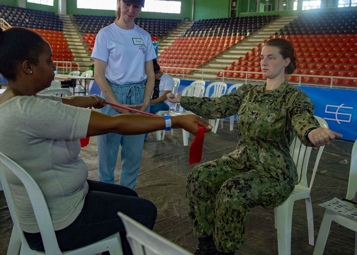 A U.S. Navy Hospital Corpsman teaches a woman exercises.