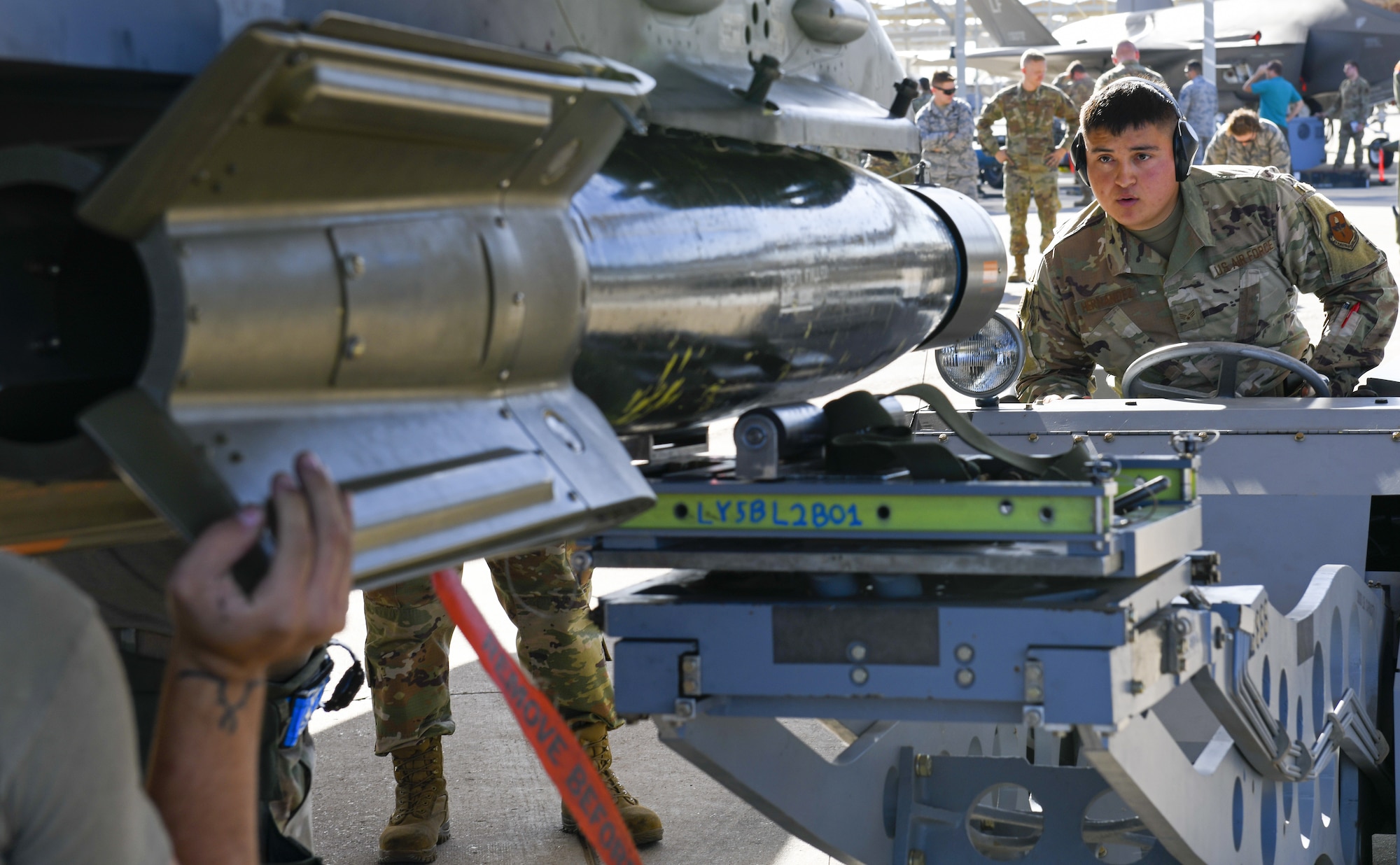Senior Airman Calvin Hernandez, 309th Aircraft Maintenance Unit weapons load crew member, directs an inert munition from a jammer onto an F-16C Fighting Falcon during the 3rd Quarter Load Crew Competition Oct. 17, 2019, at Luke Air Force Base, Ariz.