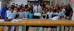 Ryan McLeod, DLA Troop Support Project G.I.V.E. coordinator, center, holds a cake and poses with students and tutors during the Project G.I.V.E. pizza party at the Benjamin Franklin Elementary School Oct. 1, 2019 in Philadelphia.