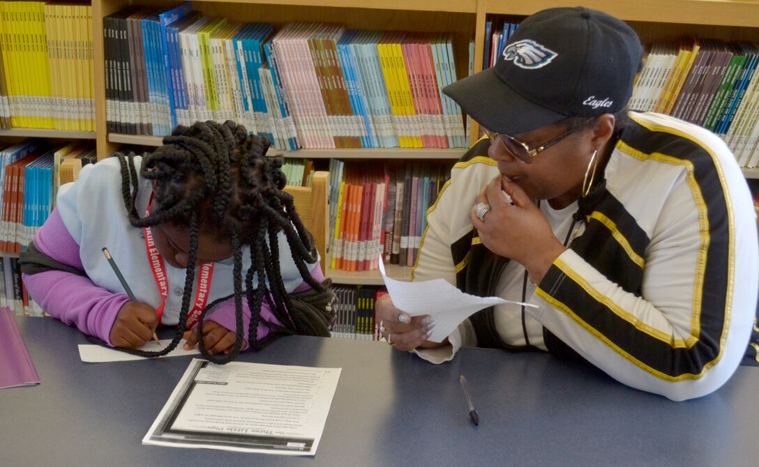 Crystal Robinson, a DLA Troop Support Project G.I.V.E. tutor, right, helps a student with schoolwork during the initial Project G.I.V.E. tutoring session for the 2019-2020 school year at the Benjamin Franklin Elementary School Oct. 15, 2019 in Philadelphia.