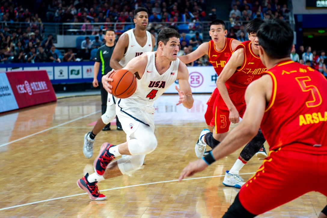 A man dribbles a basketball as he drives to the basket during a game.