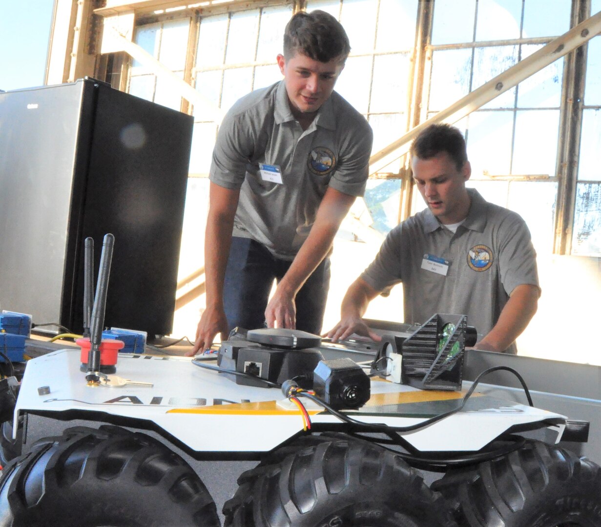 IMAGE: DAHLGREN, Va. (Sept. 19, 2019) – Michael Joram, left, and Tyler Boitnott prepare to demonstrate PERSEUS – the most recent effort in a line of projects solving the integration of high-powered electric weapon systems and electric propulsion systems aboard U.S. Navy ships. They were among a seven-member team of Sly Fox Mission 26 junior scientists and engineers who briefed military, government civilians, and defense contractors five times over the course of two days on their development of PERSEUS.  (U.S. Navy photo/Released)