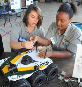 IMAGE: DAHLGREN, Va. (Sept. 19, 2019) – Emily Rabin, left, and Dominique James prepare to demonstrate PERSEUS – the most recent effort in a line of projects solving the integration of high-powered electric weapon systems and electric propulsion systems aboard U.S. Navy ships. They were among a seven-member team of Sly Fox Mission 26 junior scientists and engineers who briefed military, government civilians, and defense contractors five times over the course of two days on their development of PERSEUS.  (U.S. Navy photo/Released)