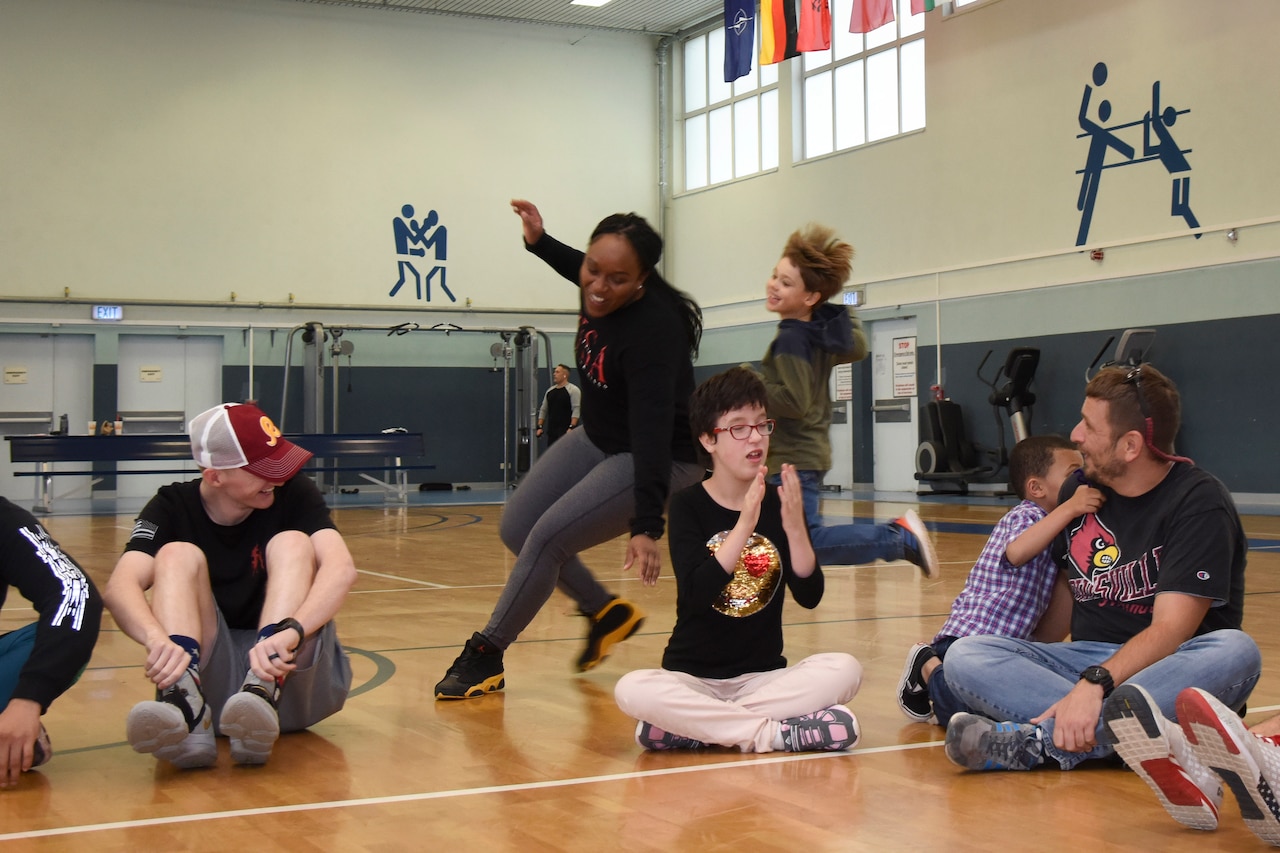 A child chases an airman as other kids sit in a circle.