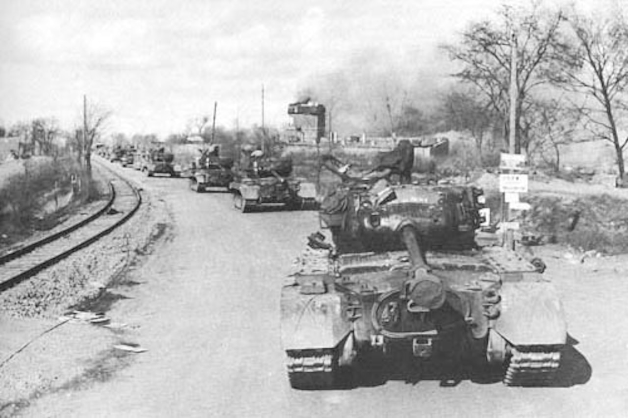 A tank convoy rolls down an empty street.