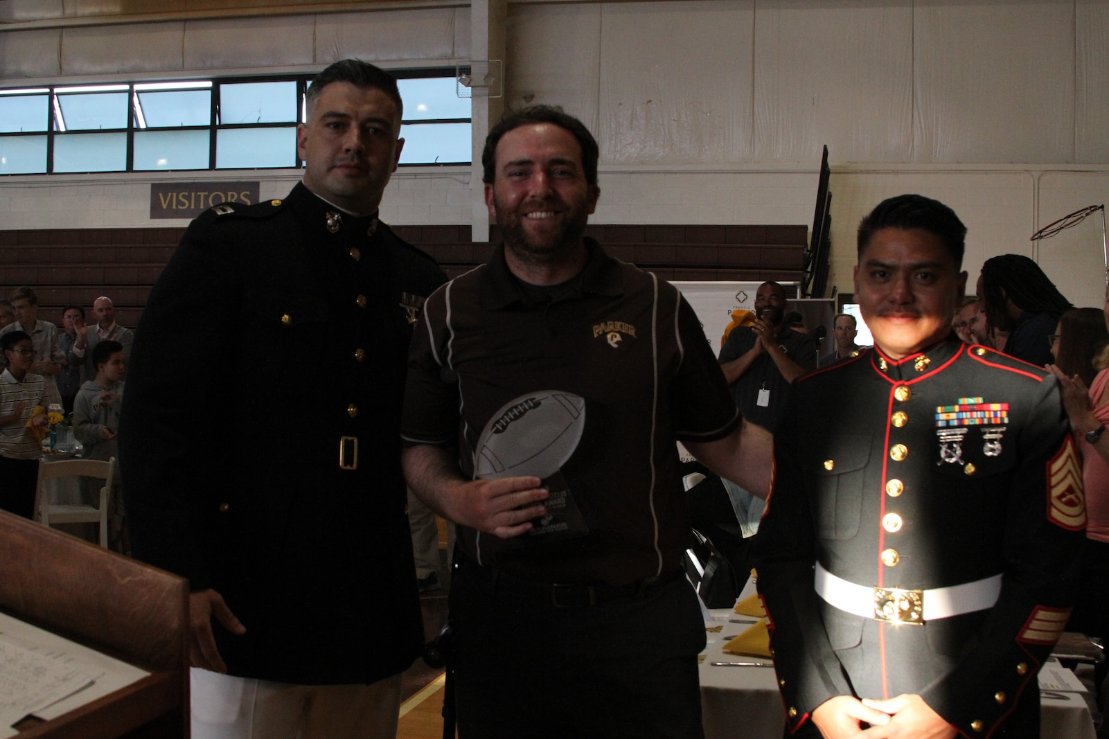 U.S. Marine Corps Capt. Tyler Simmons, the Executive Officer of Recruiting Station San Diego, presents a trophy to Matt Morrison, the Semper Fi Coach of the Year from Francis Parker High School. The Semper Fi Coach Award recognizes a high school coach who exemplefies the Marine Corps motto: Semper Fidelis - Always Faithful - and who models the Marine Corps values of honor, courage and commitment.