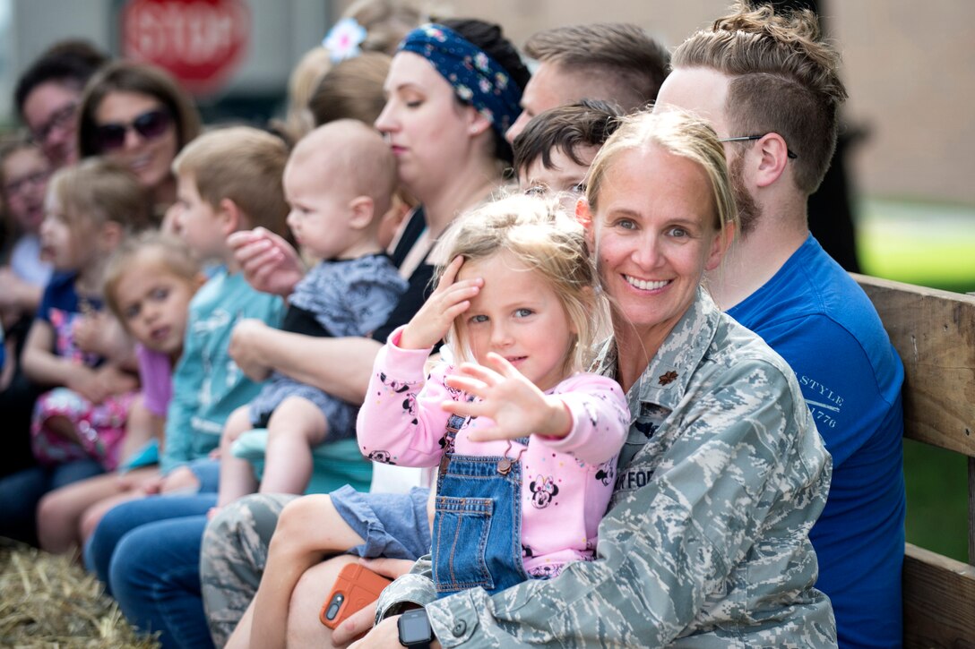 A service member holds her daughter in her lap.