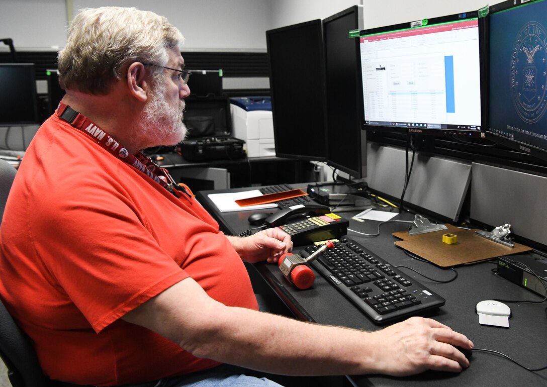 Mike Bunch, an instrument technician, looks up a part in the digital database created by Gareth Penfold, an instrumentation, data and controls engineer, to track calibration requirements for test, measurement and diagnostic equipment used in the AEDC Aerodynamic and Propulsion Test Unit at Arnold Air Force Base. (U.S. Air Force photo by Jill Pickett) (This image has been altered by obscuring a badge for security purposes.)