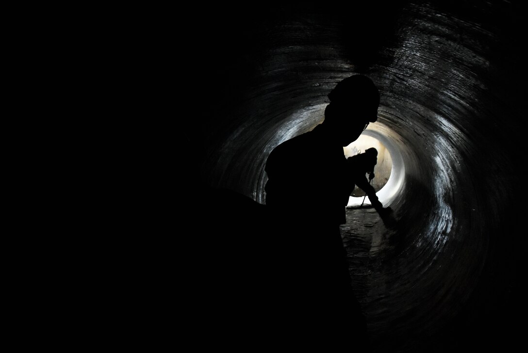 Maj. Michael Knauf looks on as Dusty Pickens sweeps water in raw water pipes near the Engine Test Facility J-3 test cell at Arnold Air Force Base during a Sept. 23 inspection of pipes recently lined with a fiber-reinforced polymer. (U.S. Air Force photo by Bradley Hicks)