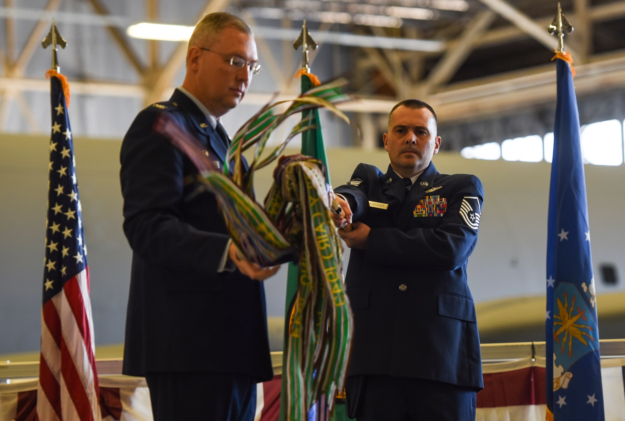 U.S. Air Force Master Sgt. Matthew Hunsinger, 97th Air Refueling Squadron superintendent, holds the squadron’s guidon as Col. Russel Davis, 92nd Operation Group commander, unrolls it during the 97th Air Refueling Squadron’s reactivation ceremony and Assumption of Command at Fairchild Air Force Base, Washington Oct. 18, 2019.