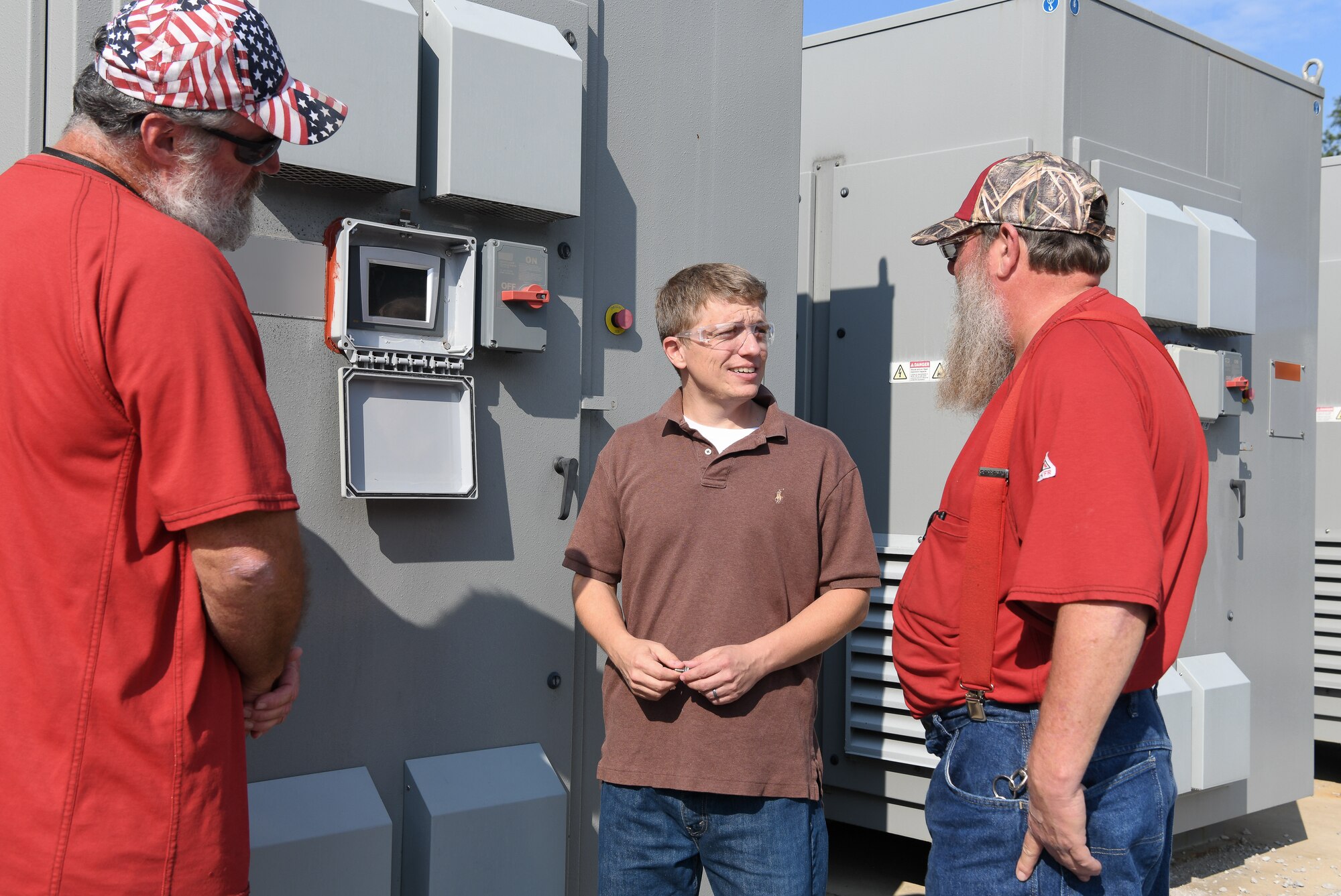 Electricians Lon Britt, left, and Robert Campbell, right, along with electrical engineer Adam Webb look at a rectifier, like one that was responsible for an un-commanded "runaway" condition, outside the AEDC Aerodynamic and Propulsion Test Unit at Arnold Air Force base. Webb improved the logic used in the Programmable Logic Controllers on the units to handle un-commanded "runaways,” which allowed him to identify the part at fault. (U.S. Air Force photo by Jill Pickett) (This image has been altered by obscuring items for security reasons.)