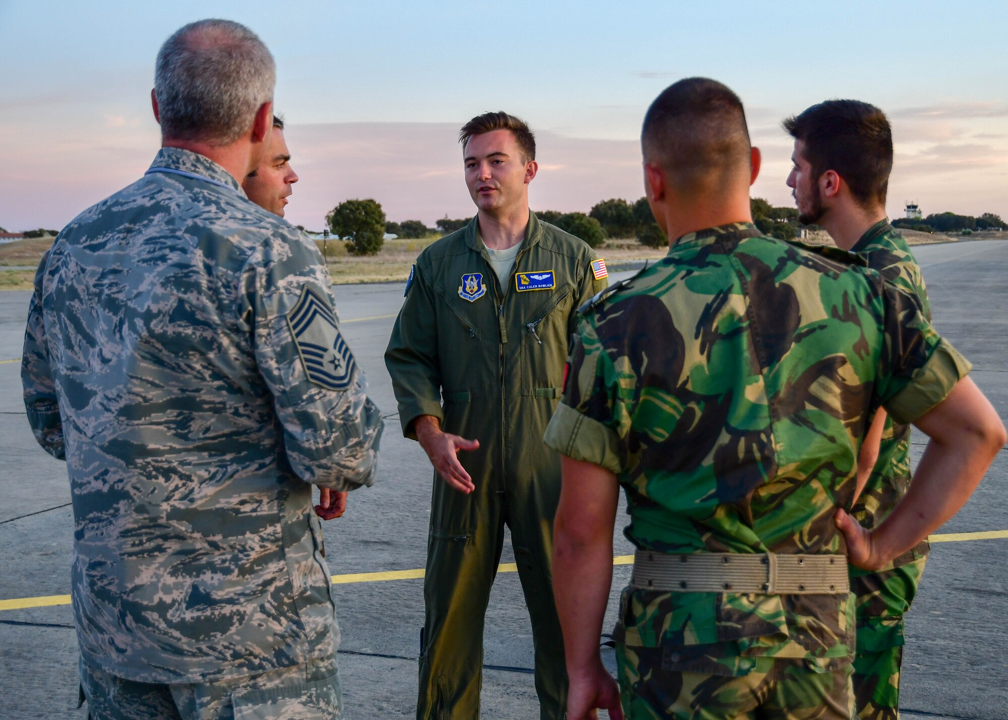Senior Airman Caleb Bowlick, a 700th Airlift Squadron loadmaster (center) speaks with Chief Master Sgt. Mark Carlisle (left), 94th Aircraft Maintenance Squadron superintendent, and members of the Portuguese air force on the flight line during Exercise Real Thaw 2019 at Beja Air Base, Beja, Portugal, Oct. 2, 2019. Real Thaw is a Portuguese-led multi-lateral flying training exercise intended to build trust and interoperability between NATO allies. (U.S. Air Force photo/Senior Airman Justin Clayvon)