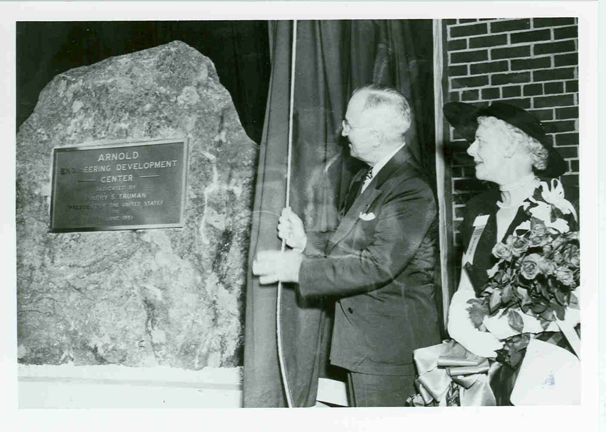During a June 25, 1951, ceremony at Arnold Air Force Base, President Harry Truman draws aside the curtain to reveal a dedicatory plaque mounted to a granite rock. The ceremony was held to dedicate the Air Engineering Development Center as the Arnold Engineering Development Center in honor of Gen. Henry H. “Hap” Arnold, who had passed away before the ceremony and whose vision was instrumental in bringing the center to fruition. Pictured with Truman is Arnold’s widow, Bee. It was 70 years ago this month that Truman signed into law the bills that allowed for the establishment of AEDC. (U.S. Air Force photo)
