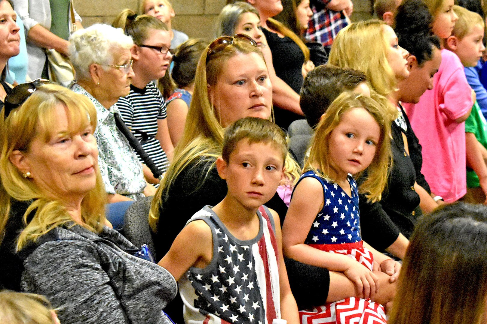 Young children and parents are seated as members in an audience.