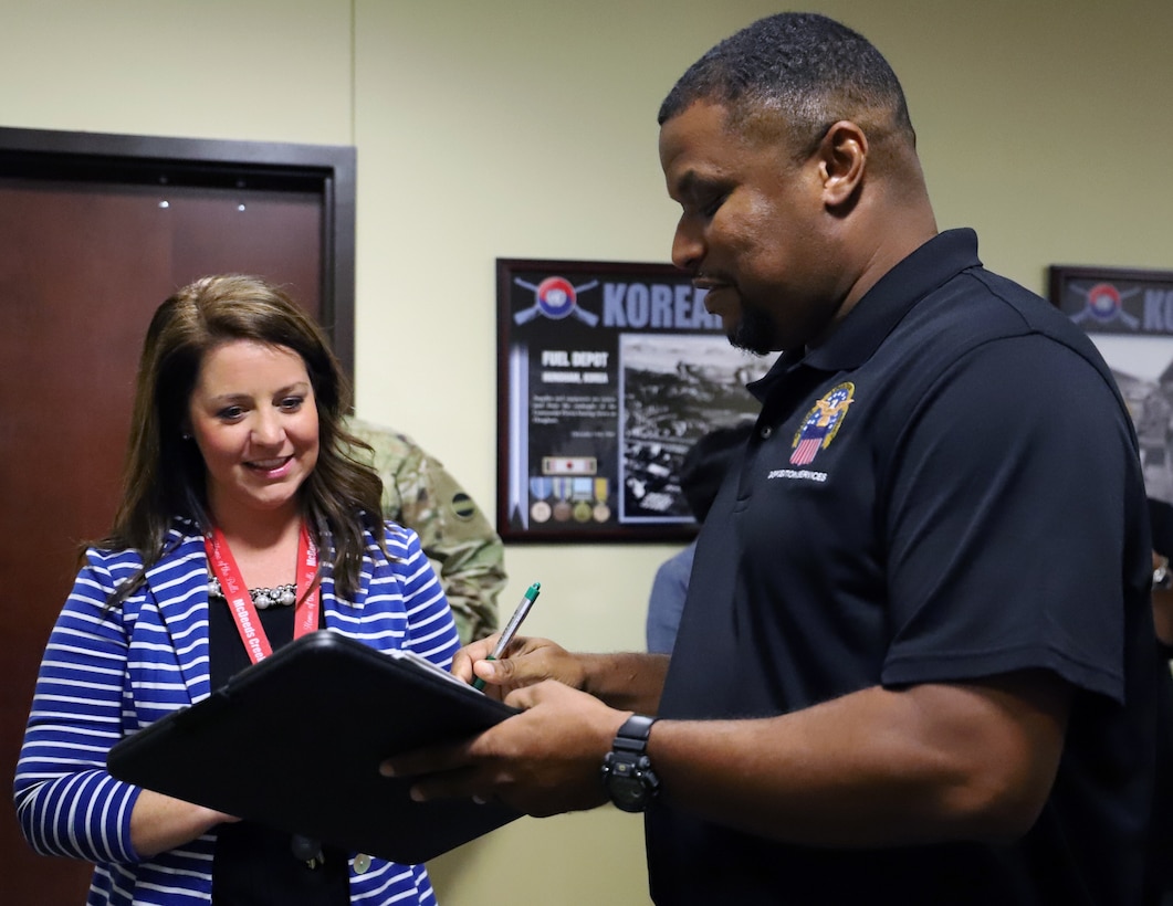 Molly Capps, principal of McDeeds Creek Elementary School in Carthage, N.C., left, signs for the computers donated to her school by U.S. Army Forces Command from Eric Garris, Defense Logistics Agency, Oct. 15.