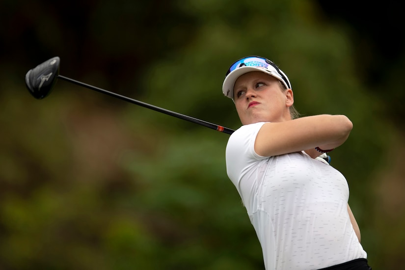 A female golfer watches her ball after hitting a golf shot.