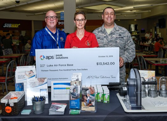 Patrick McDermott, Arizona Public Service (APS) senior account manager, presents Christine Archie, 56th Civil Engineer Squadron Portfolio Optimization office manager, and Master Sgt. John Haas, 56th CES base utility manager, with an APS energy efficiency reward through the Peak Solutions program Oct. 15, 2019, at Luke Air Force Base, Ariz.