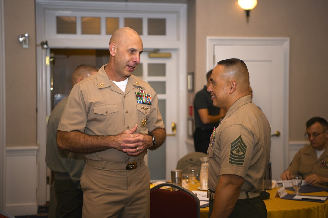 Navy Command Master Chief Christopher W. Moore, left, speaks with Marine Corps Sgt. Maj. Vincent C. Santiago during the Sergeant Major of the Marine Corps Symposium in Quantico, Va., Oct. 17, 2019. The Sergeant Major of the Marine Corps Symposium is an annual event for Marine Corps Sergeants Major to gather and discuss Corps readiness, safety and future operations.