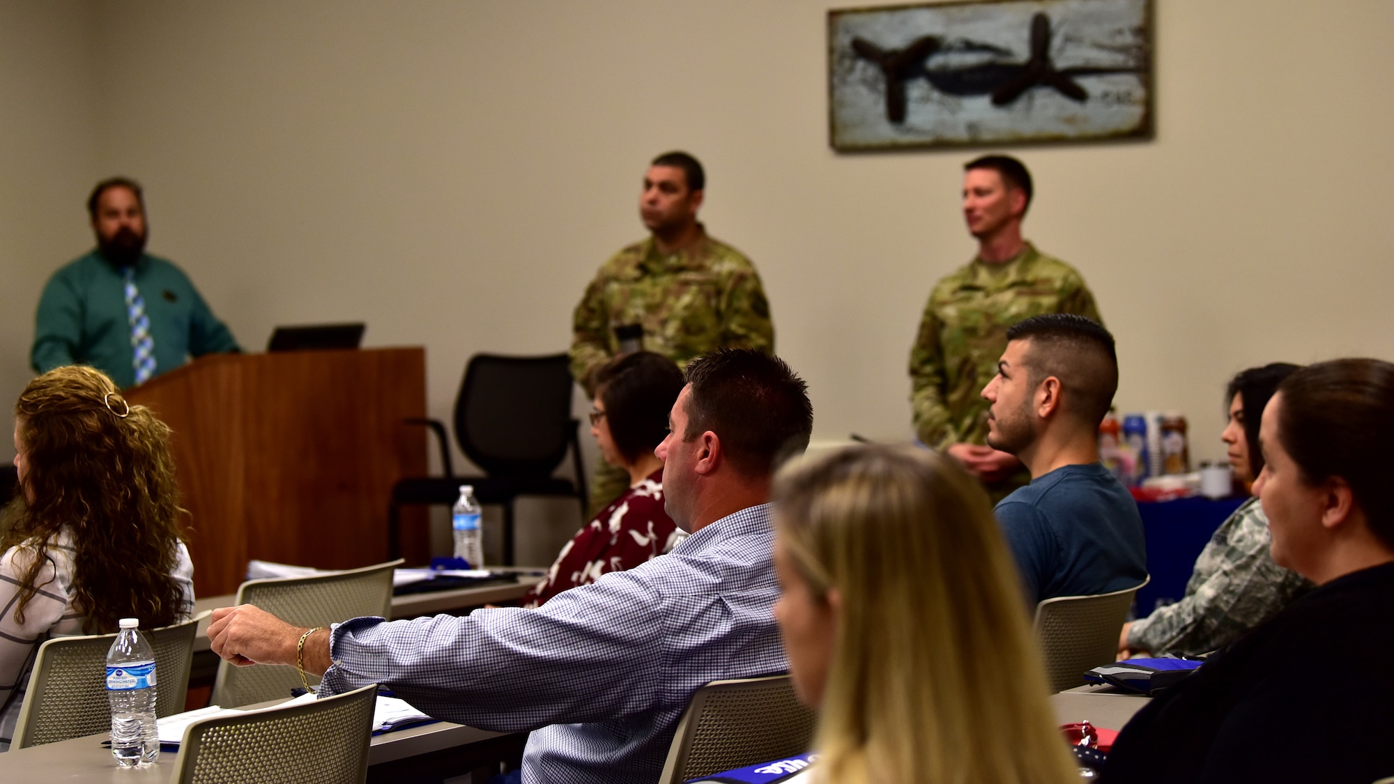 Individuals recieve a briefing in a biege room.