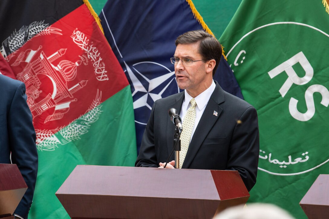 Defense Secretary Dr. Mark T. Esper speaks at podium with Afghan, NATO and Resolute Support flags behind him.