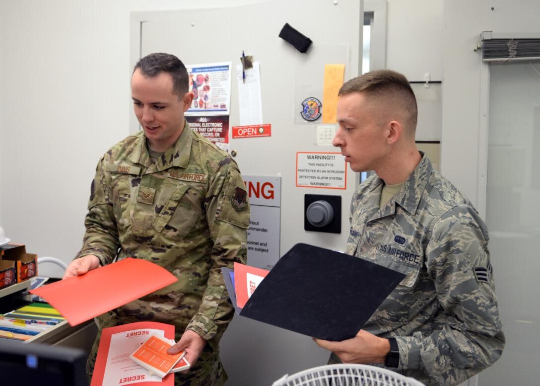 Senior Airman Daniel M. Davis, 9th Communications Squadron information system security officer, left, and Senior Airman Tyler R. Stagland, 9th CS information system security officer,  right?, take items out of a cabinet in the cybersecurity office, on Beale Air Force Base, California, Oct. 17, 2019. Davis and Stagland were preparing for a simulated inspection. (U.S. Air Force Photo by Airman Jason W. Cochran)