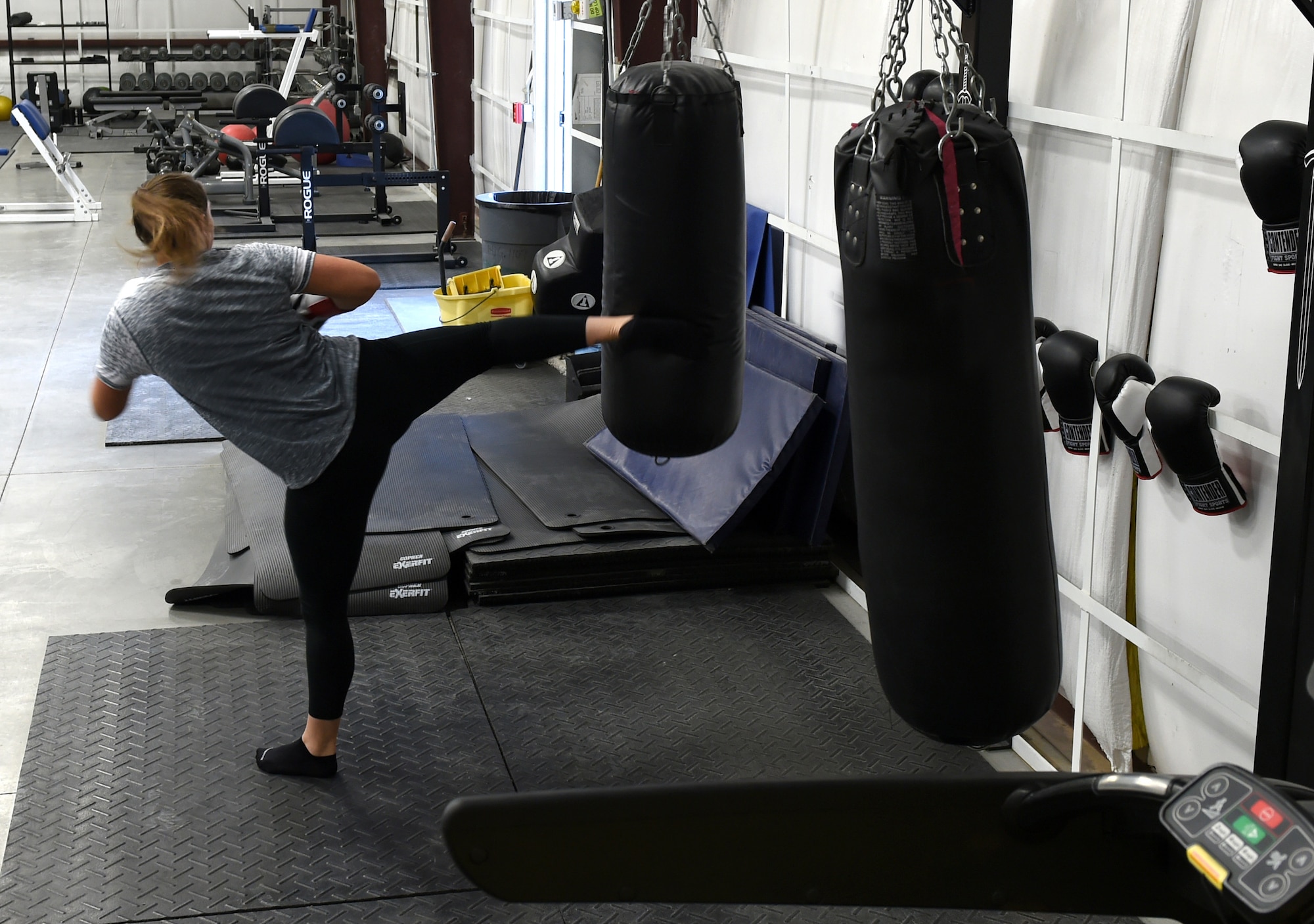 Senior Airman Stevie, 432nd Wing Staff Agency photojournalist, kicks a heavy bag in the Reaper Fitness Center at Creech Air Force Base, Nevada, Oct. 16, 2019. Equipment available for use 24/7 includes a boxing ring and Alpha Warrior Course. (U.S. Air Force photo by Airman 1st Class William Rio Rosado)