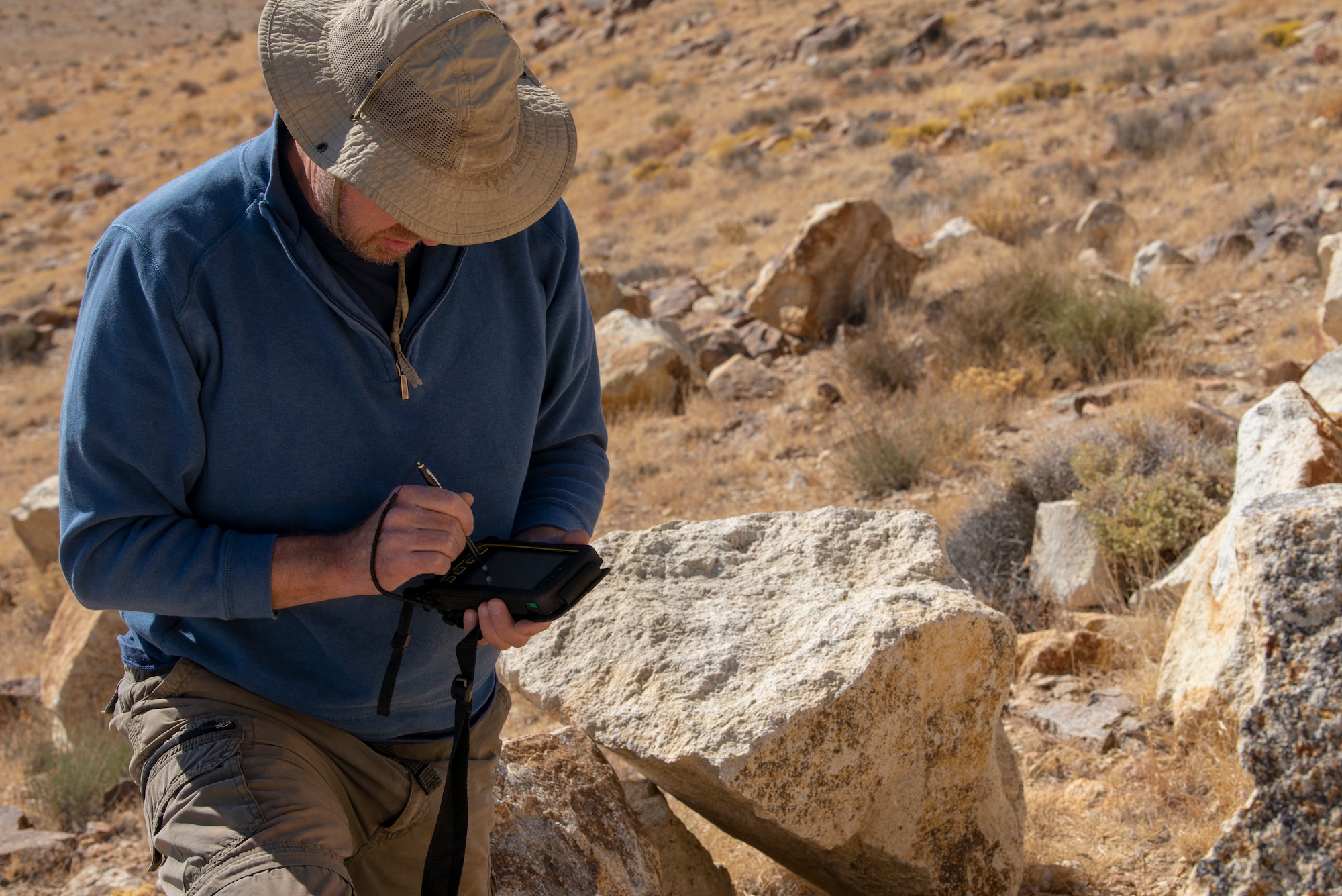 Steve Stocking, lead herpetologist with Colorado State University, documents the GPS coordinates for a rattlesnake on the Nellis Test and Training Range, Nevada, Oct. 17, 2019. The coordinates are used for the wildlife biologists to be able to find the reptiles and their dens when they go back to the sites. (U.S. Air Force photo by Staff. Sgt. Tabatha McCarthy)