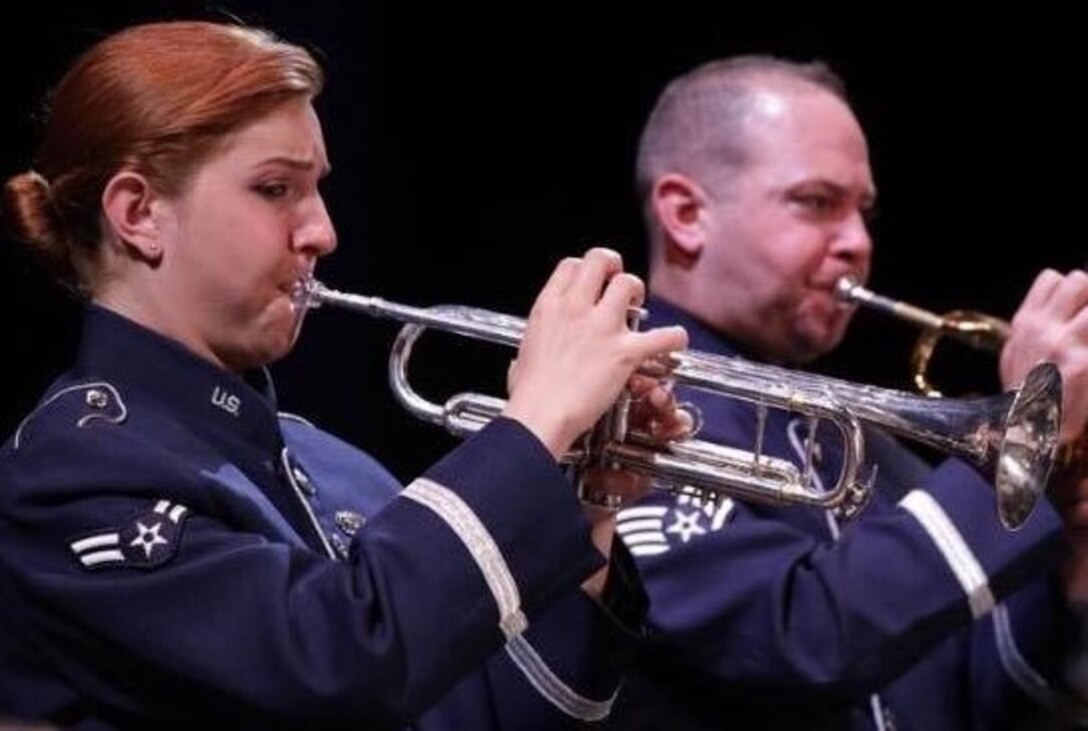 Two trumpet players perform sparkling jazz music in their blue tunic uniforms on a black background.