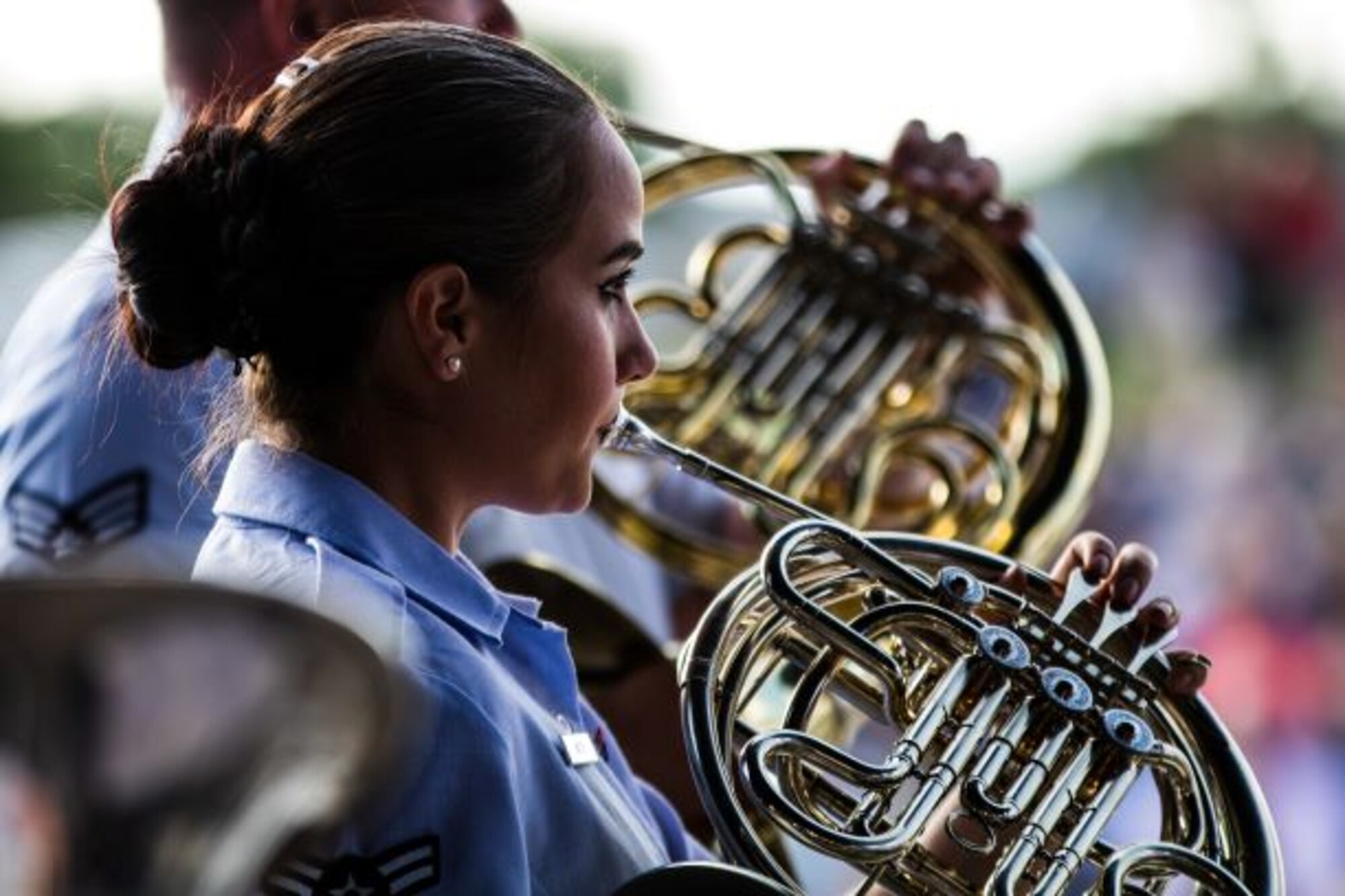 An Academy Band French horn player performs in her blue uniform during a 2019 concert band Independence Day tour.