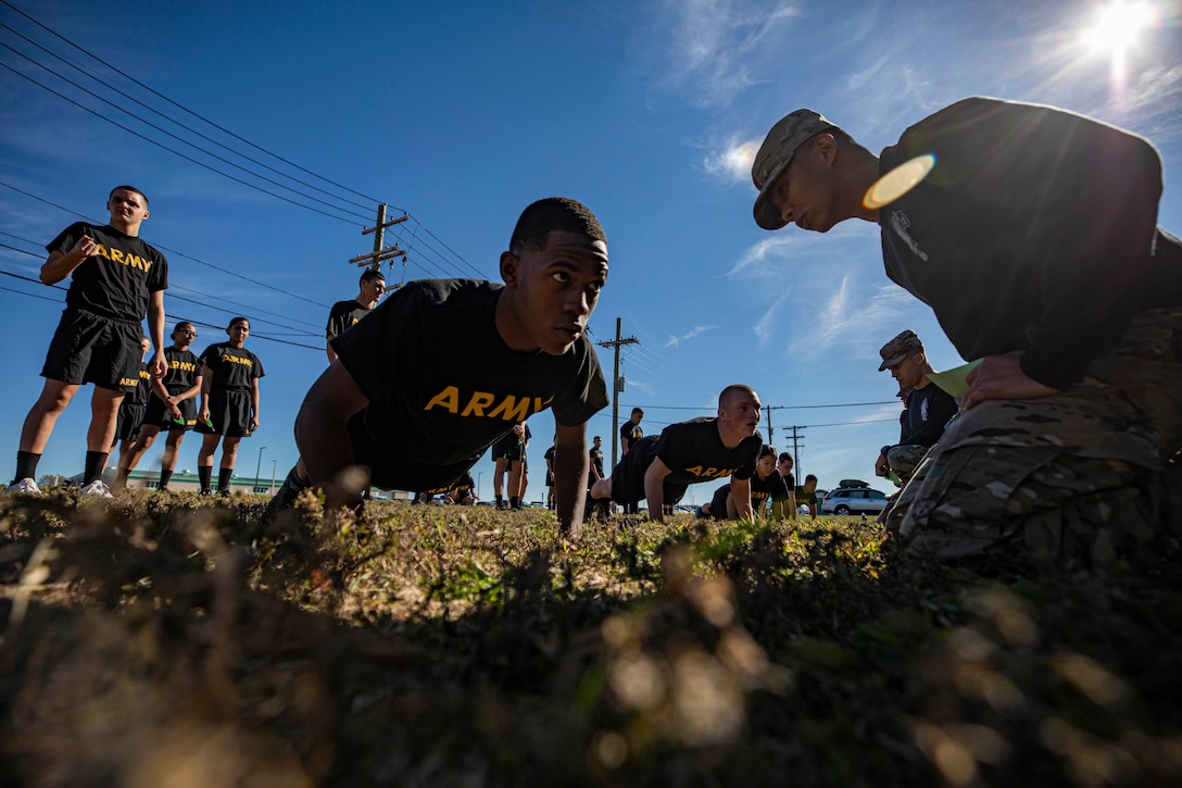 Soldiers do pushups while others stand around.