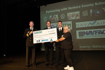 Naval Base Ventura County held a celebration Wednesday Oct. 16 distributing a check to fund FIRST Robotics programs in the county. Captain Matthew Riethmiller, Executive Officer, Naval Facilities Engineering and Expeditionary Warfare Center, (far left), Capt. Matthew Sniffin, Vice Commander, Naval Air Warfare Center Weapons Divison, Capt. Ray Acevedo, Commanding Officer, Naval Surface Warfare Center Port Hueneme Division, with Velma Lomax (far right), FIRST Robotics Regional Director-Southern California, hold the check that was presented at Oxnard College.