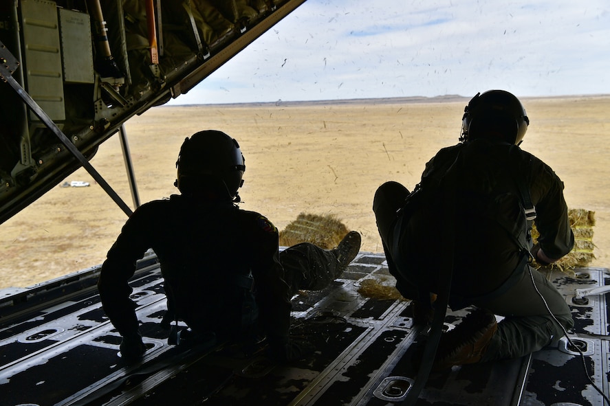 Loadmasters push a bundle out the back of a C-130.