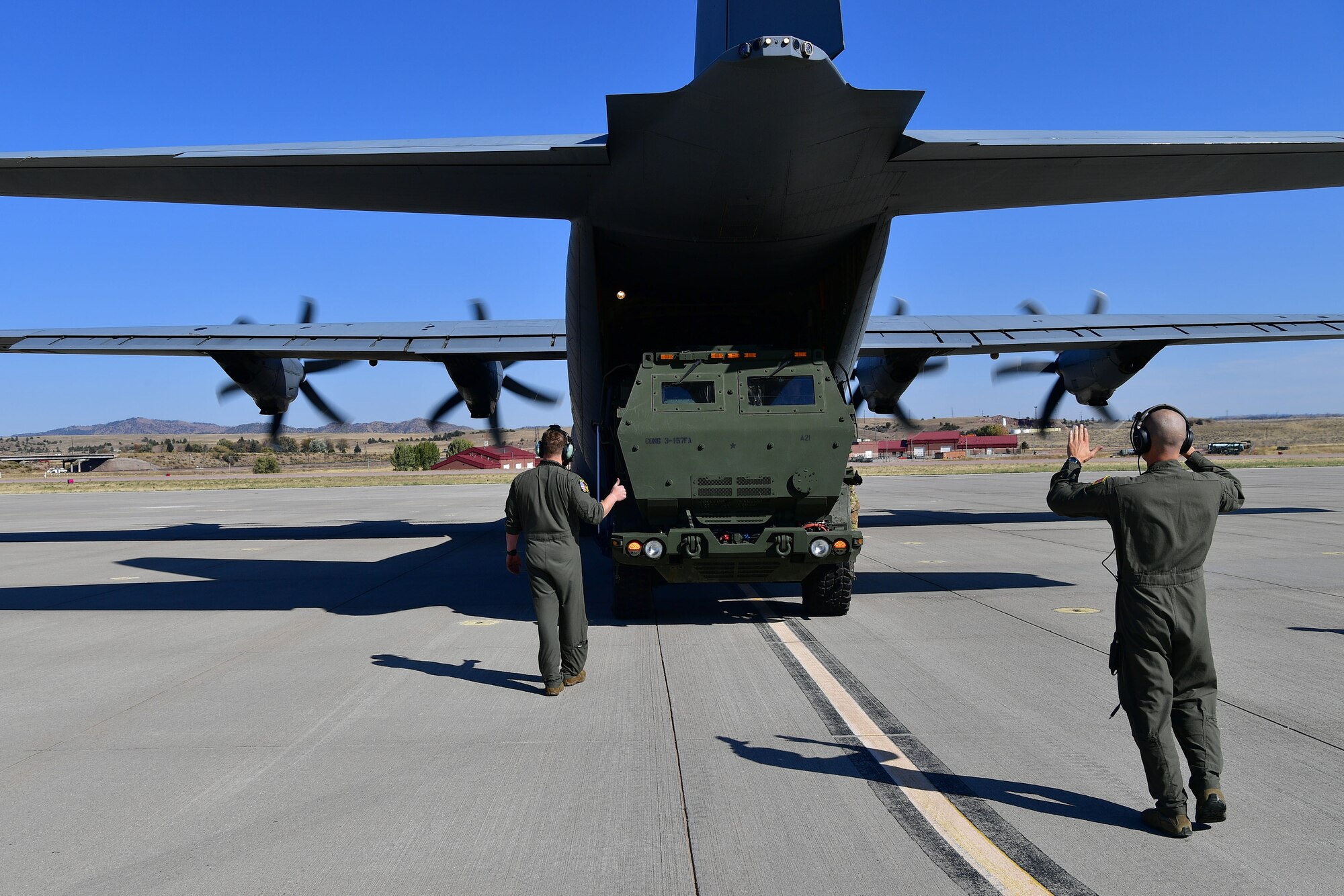 Loadmasters guide a HIMARS onto a C-130.