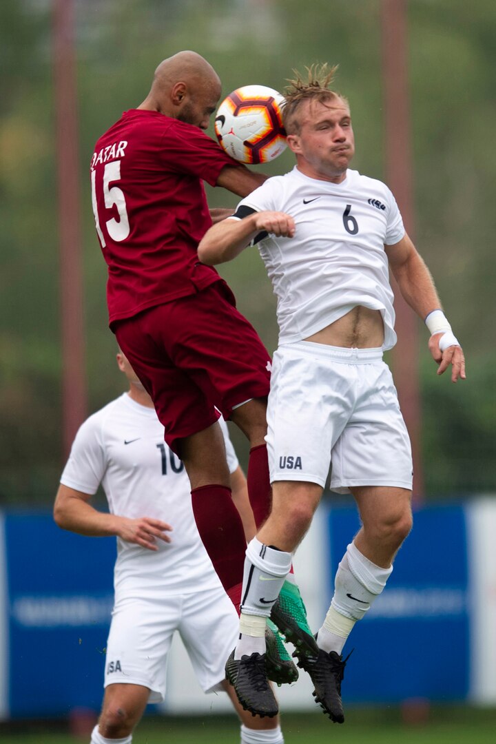 Two soccer players try to control the ball with their heads.